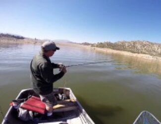 A guy on a boat fishing on a lake